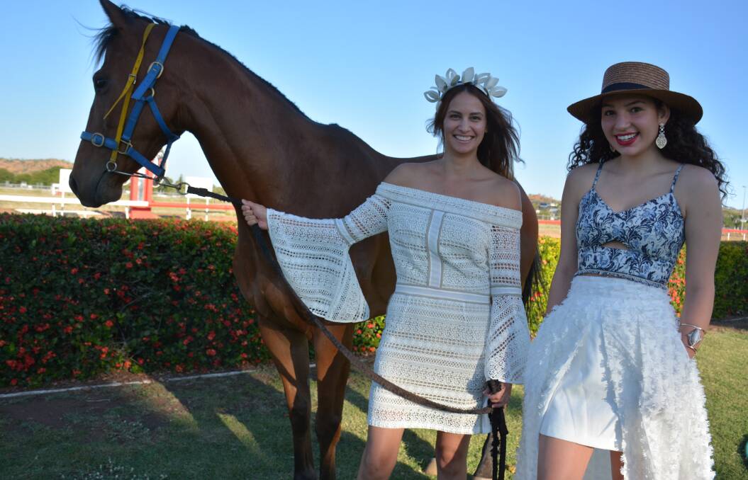 DOLLED UP: Danielle Yamaguchi and Piper Martin dressed in We Are Kindred racewear, sold locally at Loft 23. Racehorse Mishani Trader looks eagerly at the Mount Isa race track, which he races on in the local maiden race. Photo: Chris Burns.  
