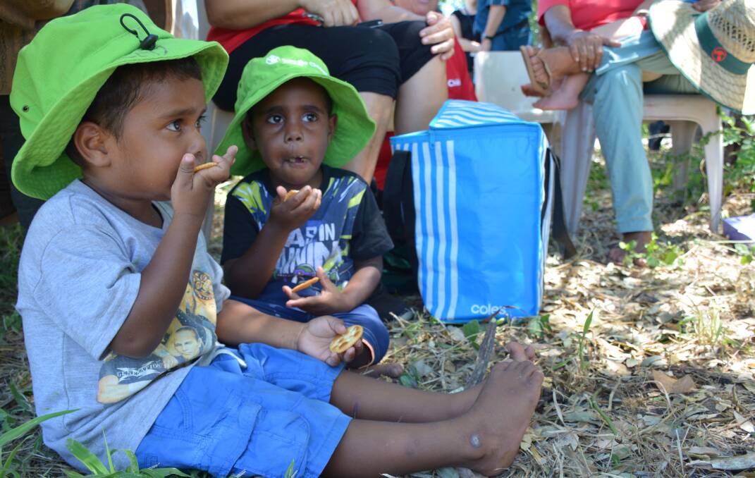 SNACK TIME: Children eat under the shade during the speeches made during the community garden ceremony. 