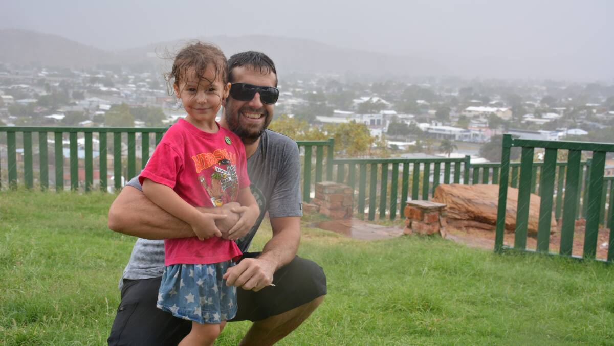 Cheerful: Graham and Milla Peden, 4, watch the storm from the Mount Isa lookout on Wednesday afternoon. 
