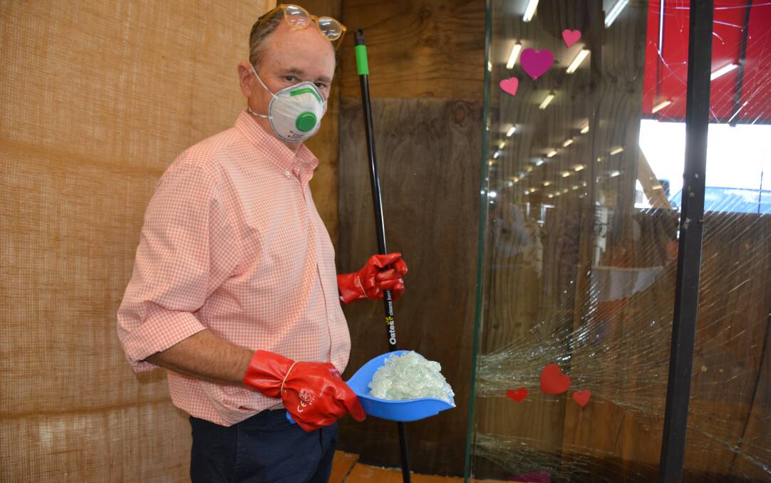 Playtime owner Phillip Beard takes necessary precautions while cleaning the front of the damaged store on Wednesday morning. Photo: Chris Burns. 