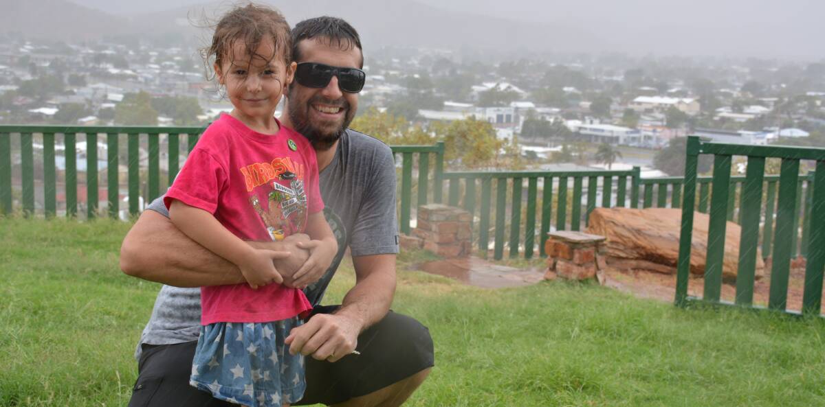 Cheerful: Graham and Milla Peden, 4, watch the storm from the Mount Isa lookout on Wednesday afternoon. 