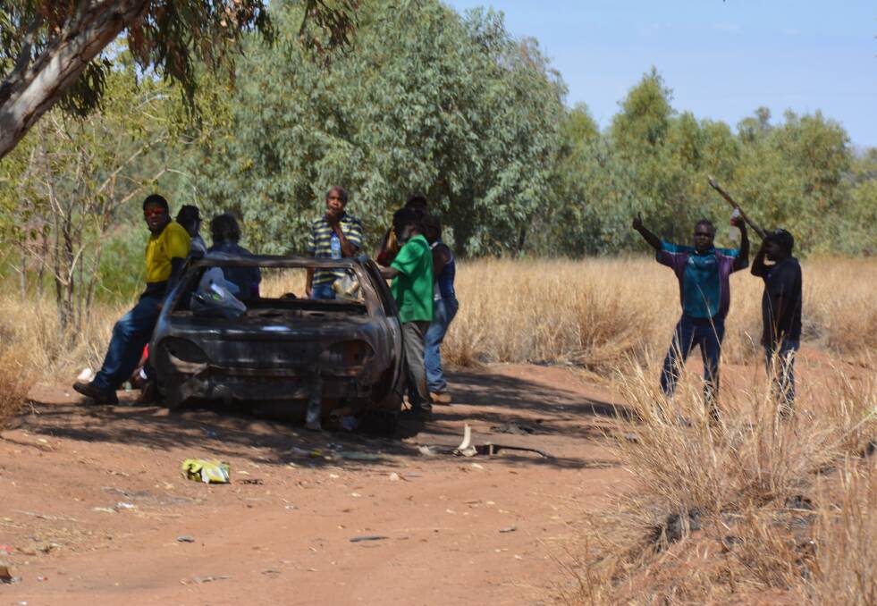 Gathering: A group of men at a track near Dinner Camp where riverbed dwellers camp. They stand near one of several damaged cars that remain near the dried Leichhardt Riverbed behind the bowls club on Mount Isa Island. 