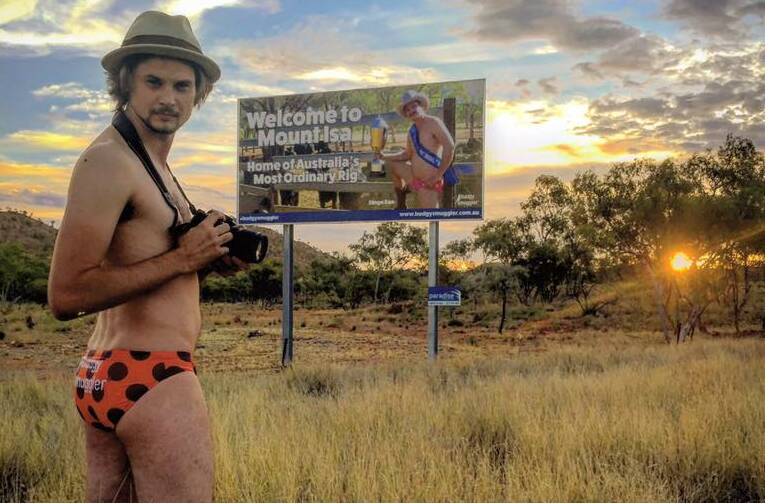 BADLY IN NEED OF A TAN: Chris Burns takes a photo of Dan Leyden's billboard while wearing budgie smugglers.