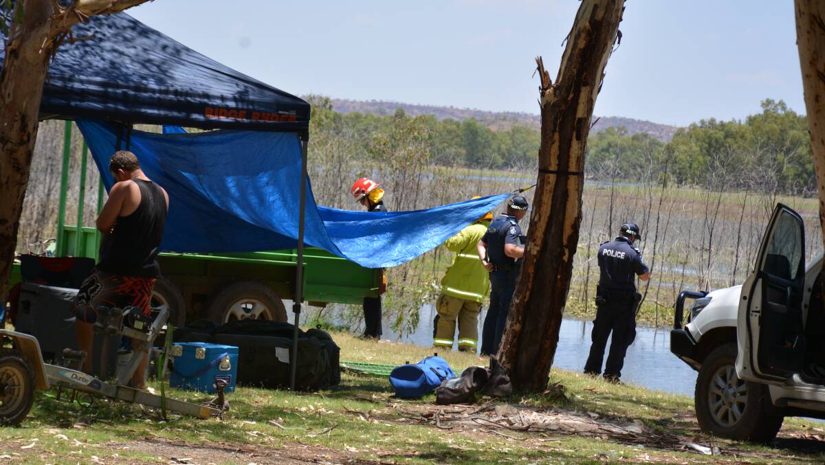 Police and QFES workers wait at Lake Moondarra shortly after the man and six-year-old boy were transported from the site. Photo: Chris Burns. 