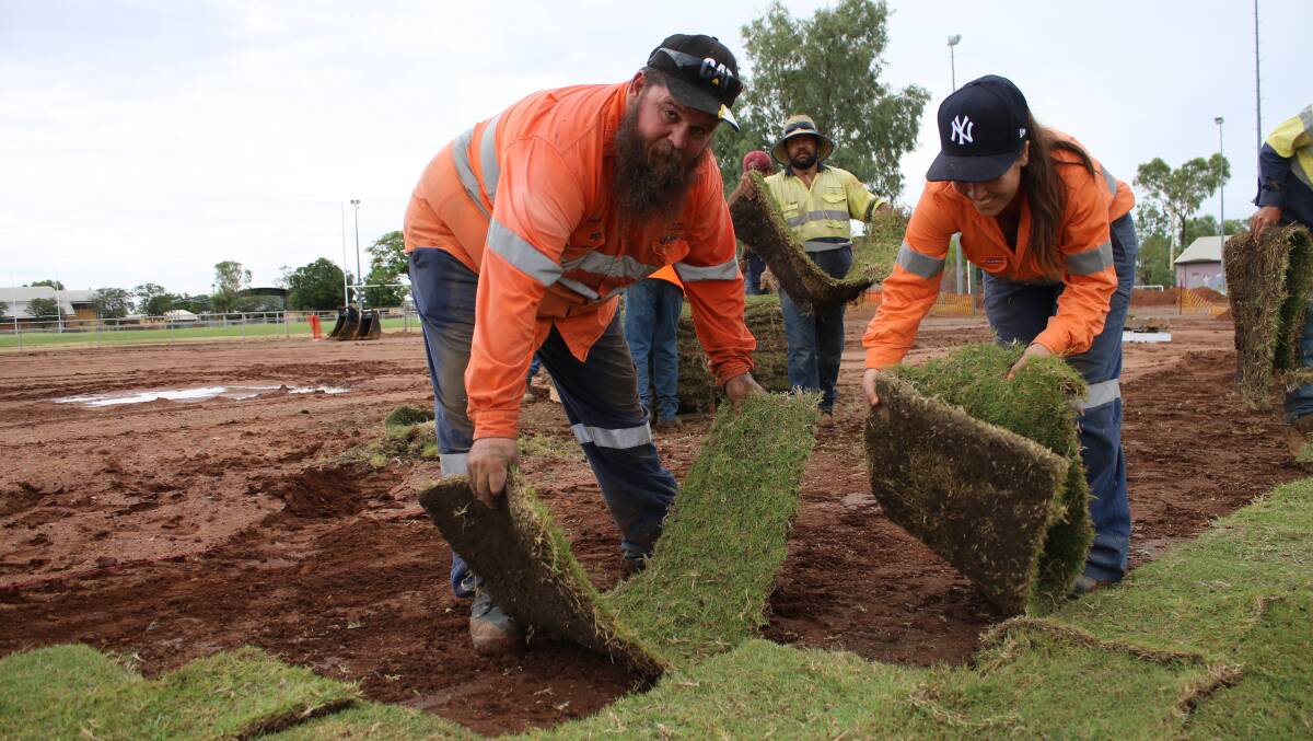 GETTING STUCK INTO IT: Ernest Henry's surface operations supervisor Jason Macnamara and community relations advisor Emily White lay down turf at the Recreation Ground. Photo: Ernest Henry Mining. 