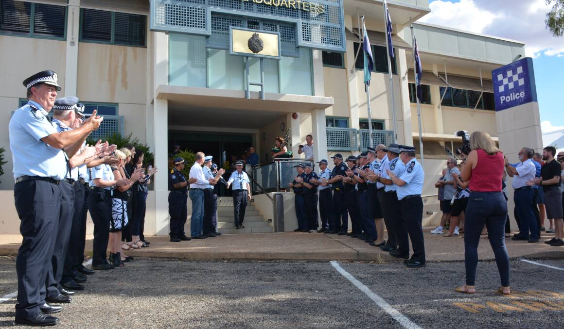 Inspector Kidd leaves the Mount Isa Police Headquarters during the piping ceremony, as Commissioner Ian Stewart (left) applauds along with other senior officers. Photo: Chris Burns. 