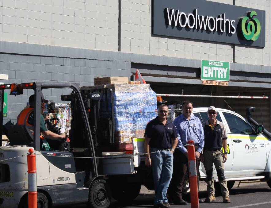 STOCKING UP: ADG's Matt McKeown and Doug Gage receive water and food donations form Woolworths' Mount Isa store manager John Neal (centre) on Monday. Photo: Esther MacIntyre