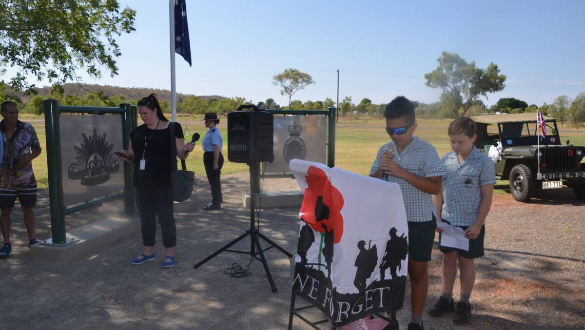 St Joseph's School captains, Eric Asomah and Ryan Philp, give a Remembrance Day tribute to fallen servicemen buried at the cemetery in Mount Isa.