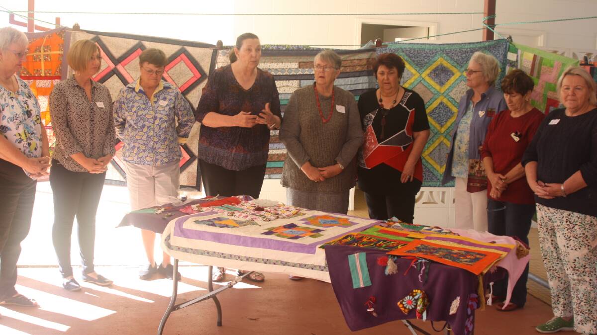 Mount Isa Quilters Group members present Betty Kiernan of the Laura Johnson Home with quilts, fidget blankets, and placemats.