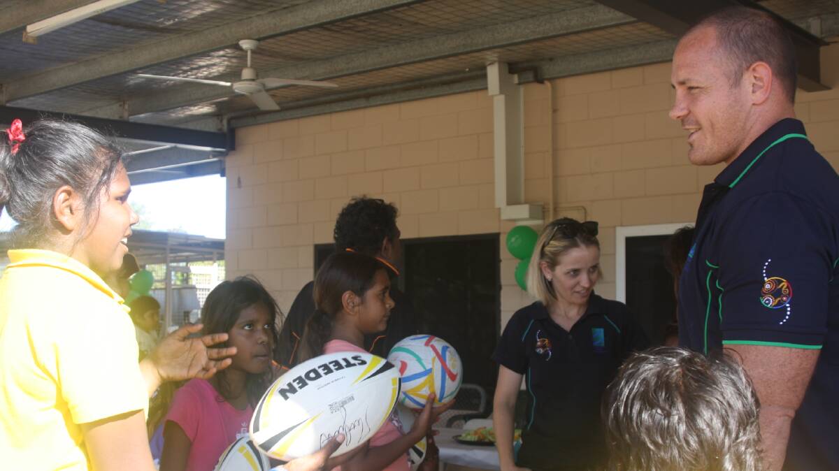 Mount Isa kids get their rugby balls signed by Queensland rugby league star, Matt Scott, at Centacare's barbecue on Friday. Photo: Esther MacIntyre