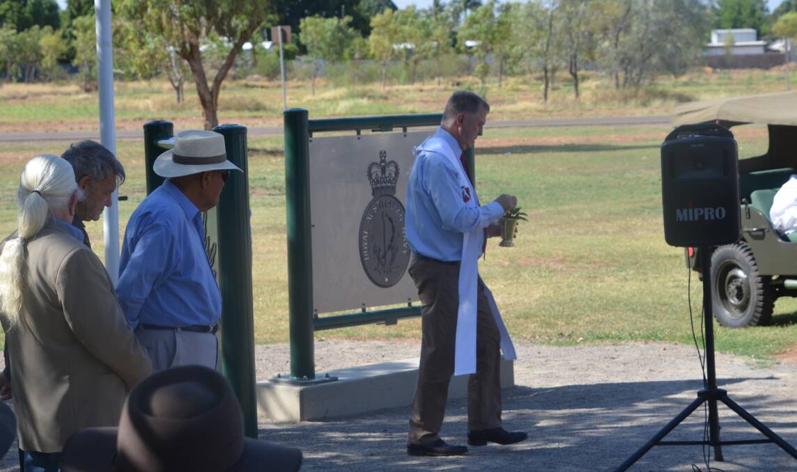 Father Mick Lowcock sprinkles holy water while blessing the new signage and the final resting place of the Mount Isa.
