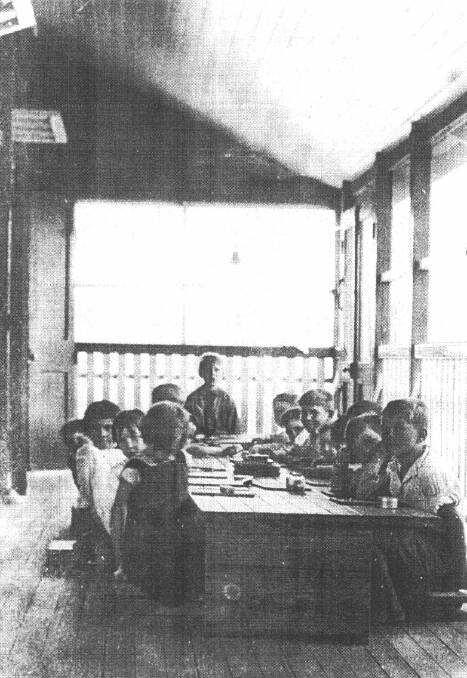 School: George Beard and classmates with seated planks at improvised desks made of packing cases on the verandah of Town State School.