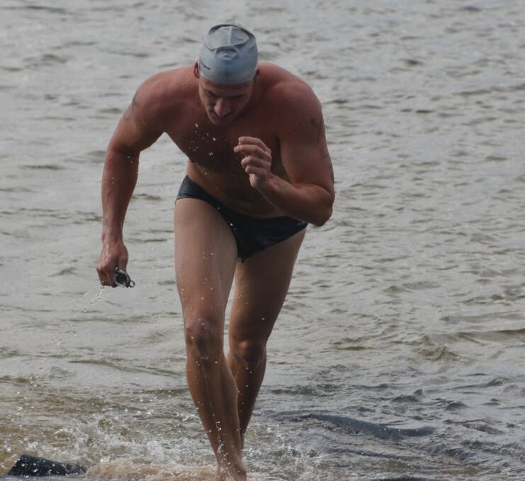 HARD YAKKA: James Stewart is first out of the water in the corporate triathlon. Photo: Derek Barry