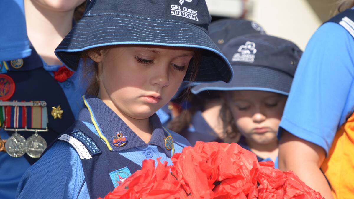 RED POPPIES DANCE: One of the girl guides inspects her poppies ahead of laying them at the Mount Isa cenotaph. Photo: Derek Barry