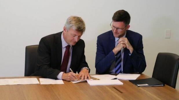 Genex executive director Simon Kidston and Energy Minister Mark Bailey sign the Palaszczuk government's first Solar 150 formal deed of agreement. Photo: Supplied