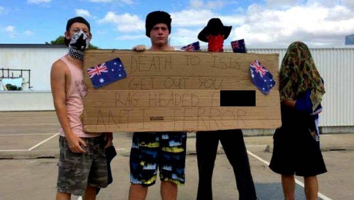 Men stood on top of a Townsville shopping centre holding a racist sign in the wake of the Sydney siege. Photo: Facebook