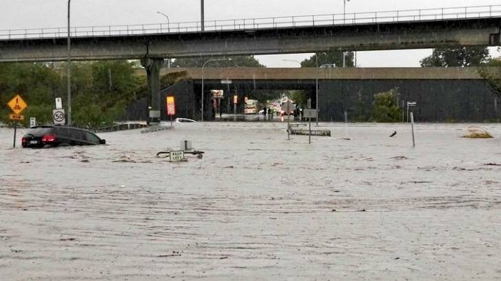 Queensland weather. A car floats away on what was previously roadway near Toombul Shopping Centre. Photo: Andrew Kos - ABC