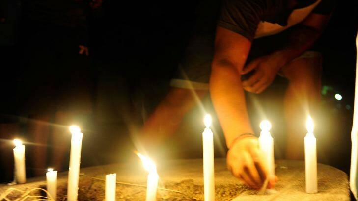 A candlelight vigil is held in the street where eight children died in a multiple stabbing in the suburb of Manoora. Photo: Ian Hitchcock