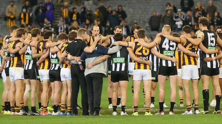 The huddle that ushered in the weekend - Collingwood and Hawthorn players link arms in tribute to Phil Walsh. Photo: Quinn Rooney