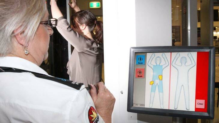 A passenger being screened by a body scanner.