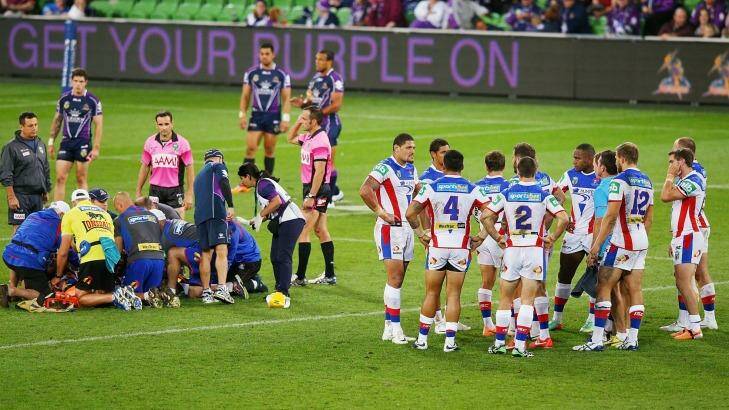 Knights players huddle as Alex McKinnon of is prepared to be carried off on a stretcher after the tackle from Jordan McLean that left him a major spinal injury. Photo: Michael Dodge