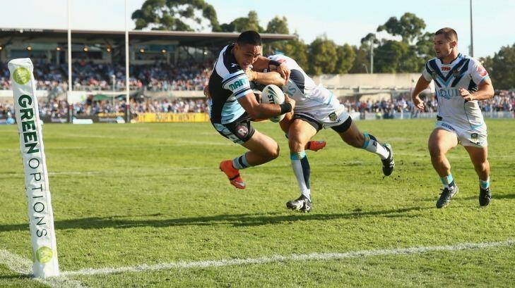 What a put down: Valentine Holmes of the Sharks is tackled as he scores try in the corner. Photo: Mark Kolbe