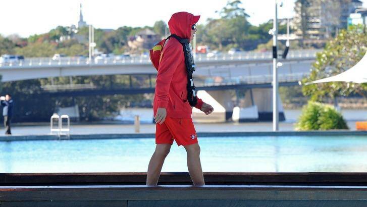 A Lifesaver at the pools at Southbank rugged up as cold weather hits south-east Queensland. Photo: Bradley Kanaris