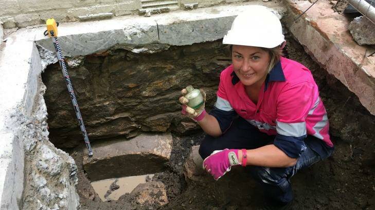 Archaeologist Tina King with a WWII-era bottle found in the test pit at the Harris Terrace. Photo: Cameron Atfield