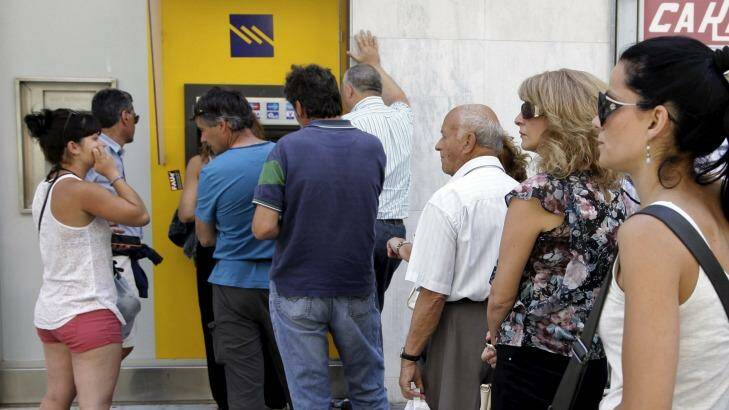 People line up to withdraw cash from an automated teller machine on the island of Crete. Photo: Stefanos Rapanis
