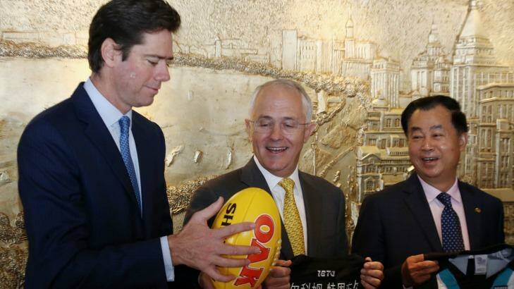 Prime Minister Malcolm Turnbull watches AFL chief Gillon McLachlan catch a Sherrin during a signing ceremony with Guojie Gui from Shanghai CHEN real estate in Shanghai on April 14. Photo: Andrew Meares