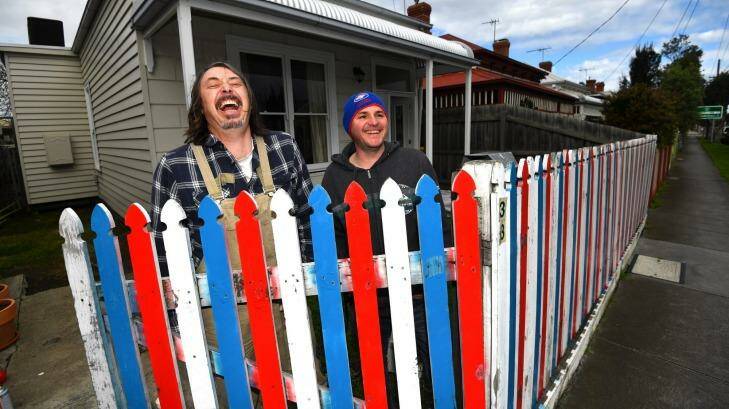 James Best (left), of Seddon, painted his front fence in Bulldogs colours after losing a bet with his neighbour Paul Leworthy. Photo: Joe Armao