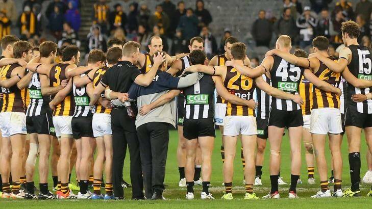 Both sides huddled together in the middle of the ground after the game to pay respect to Phil Walsh. Photo: Quinn Rooney