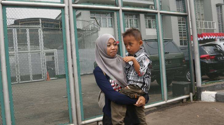 Yayah Heriyah, the wife of Syahrial, one of the cleaners jailed for alleged sex abuse at Jakarta Intercultural School, carries her son Muhammad Farid outside Jakarta's Cipinang prison.   Photo: Tatan Syuflana