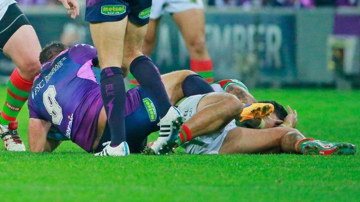 Cameron Smith of the Storm kicks Issac Luke  while being tackled by David Tyrrell. Photo: Scott Barbour