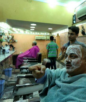 Brave face: Asaad Matoori makes the sign for a trigger while discussing Islamic State at a barber's shop in Baghdad. Photo: Kate Geraghty