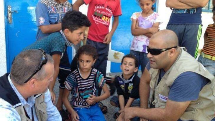 Mohammed al-Halabi, right, is seen talking to children in his work as Gaza program manager for World Vision. He has been accused of funnelling the charity's donations to the Palestinian Islamist movement Hamas. Photo: World Vision International
