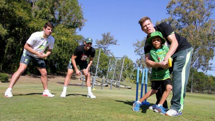 Carlin Renoug, 8, from Cherbourg gets some cricketing tips from cricketers James Faulkner, Moises Henriques and Pat Cummins at Allan Border Field, Albion.  Photo: Michelle Smith