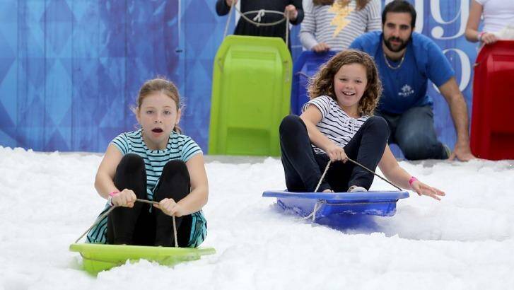 Sienna Crocket, 10, and Lottie Nehill, 10, try out the toboggan at the Winter Festival being held in King George Square. Photo: Michelle Smith