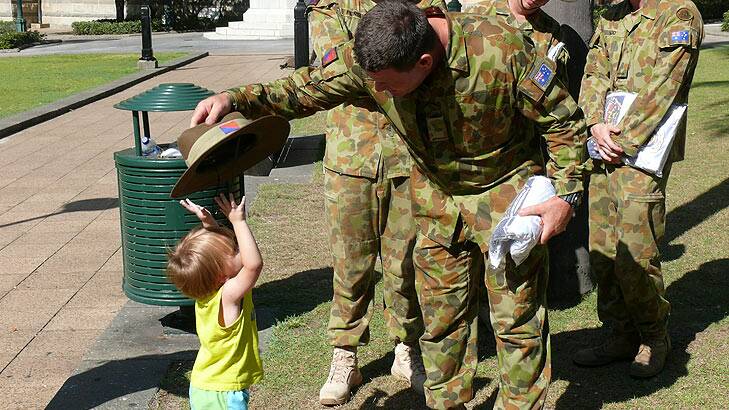 Soldiers take a break from fundraising to play with a young civilian. Photo: Supplied