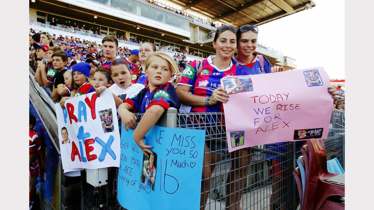 Jacinta Foster of Windale (white shirt), Chloe Marsh of Beresfield (blue sign), Sarah & Emma Gardner of Maryland (pink sign) with messages of support for critically injured Knights player Alex McKinnon. Pictured at the entrance to the tunnel while waiting for the teams to run out. Photo: MAX MASON-HUBERS 