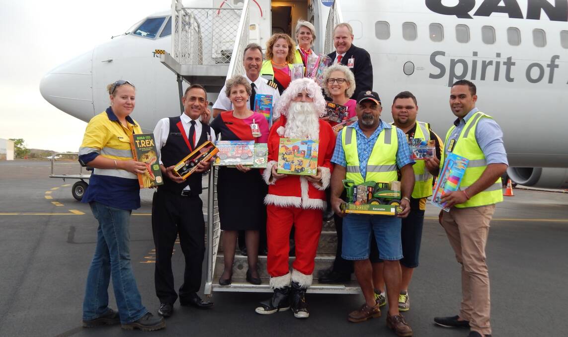 CHRISTMAS SPIRIT: Qantas workers and Father Mick’s men’s group, including Santa, are ready to deliver this year’s presents. 