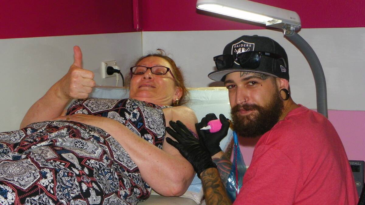 READY:  Julie Spiller, 54, gives tattooist Chris Spyrou of Cairns the thumbs-up at her turn. - Picture: JOHN WILSON