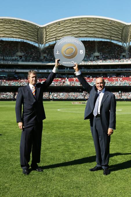 SACA President, Andrew Sinclair and SANFL President, John Olsen holds up a symbol to recognise the coming together of football and cricket as part of the opening ceremony before the round two AFL match between the Port Adelaide Power and the Adelaide Crows at Adelaide Oval on March 29. Photo: Getty