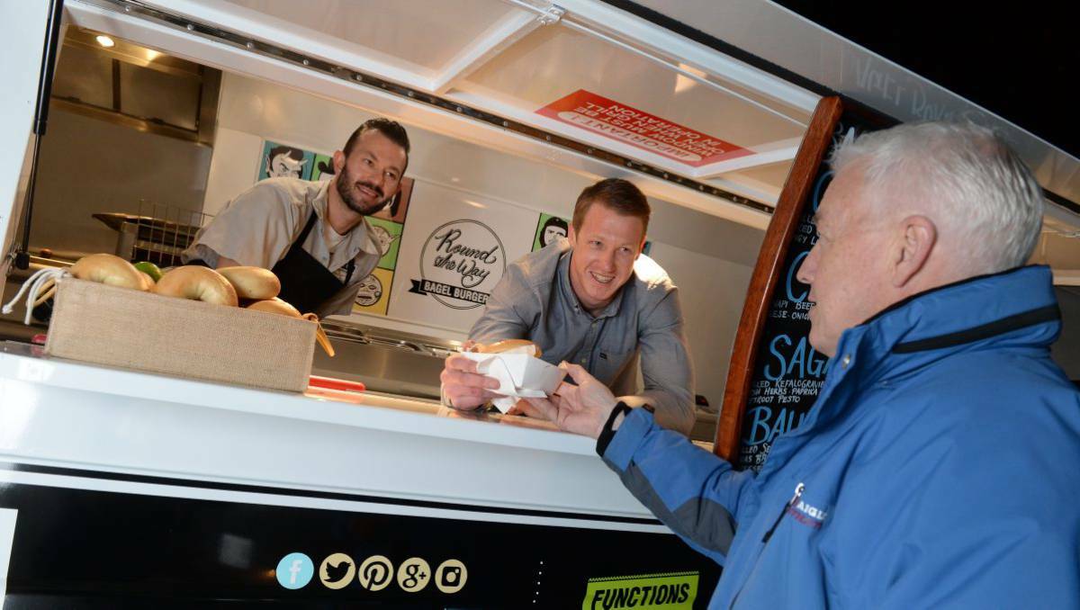 Ryan Slater and Peter Marios serve customer Trevor Slater at their new bagel burgers food van, which began business on Friday night in Ballarat. Picture: Kate Healy