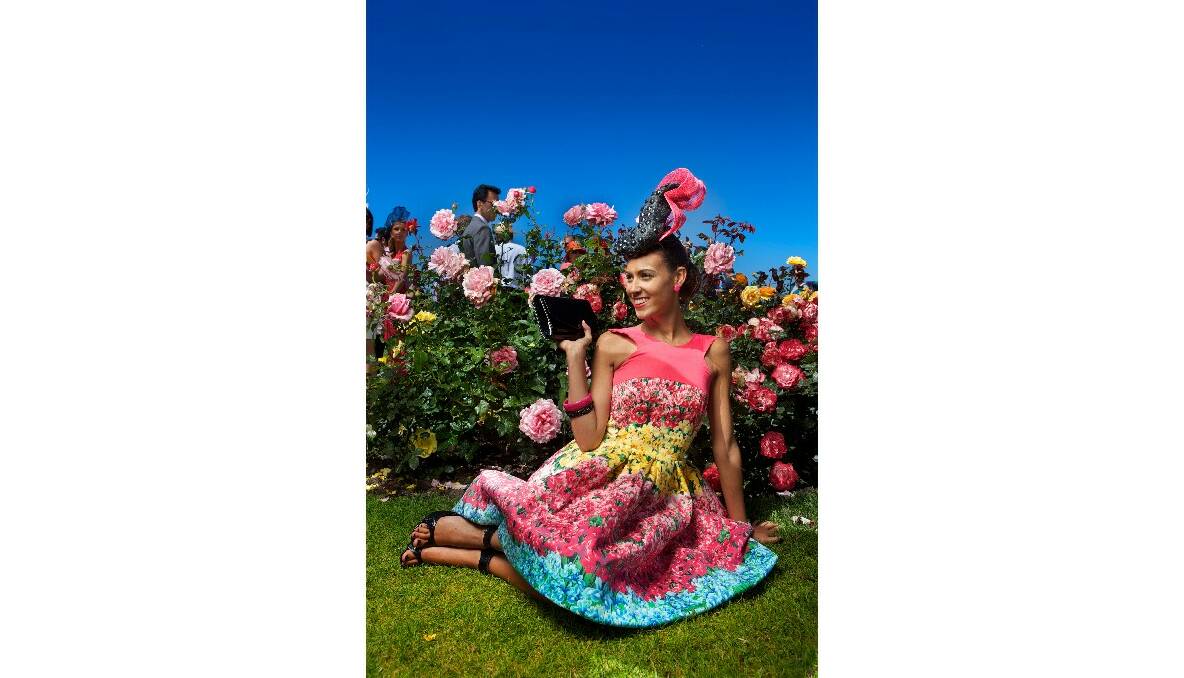 In a dress made by her grandmother (Sandra Robson) Amy Robson sits among the roses at the Melbourne Cup Fashions on the Field. Picture by Simon Schluter.