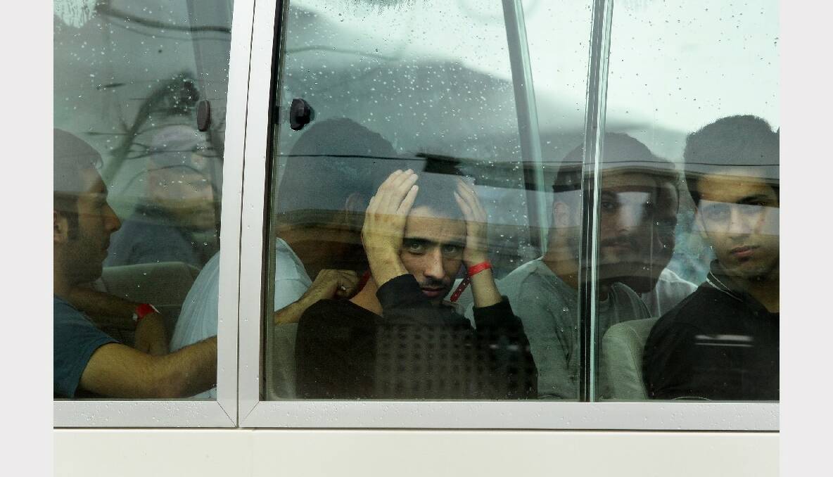 Pezhma Ghorbani (centre,hands on head) 26 from Iran looks out the window of the bus after arriving on the second plane carrying asylum seekers to Manus Island in Papua New Guinea. Photo: Kate Geraghty