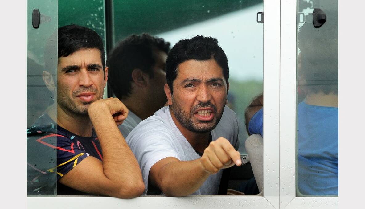 Reza Mollagholipour (right) 35 from Iran yells out that he has family in Brisbane from the window of the bus after arriving on the second plane carrying asylum seekers to Manus Island. Photo: Kate Geraghty