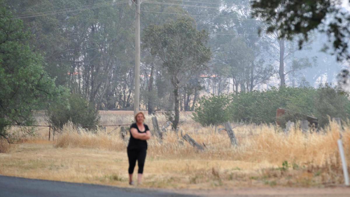 A nervous resident looks on as the blaze approaches the township of Stockinbingal. Picture: Michael Frogley