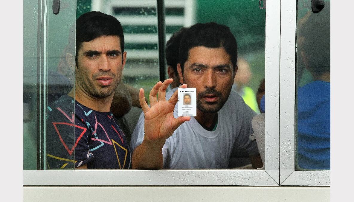 Reza Mollagholipour (right) 35 from Iran holds his ID card out the window of the bus after arriving on the second plane carrying asylum seekers to Manus Island in Papua New Guinea. Reza has family in Brisbane. Photo: Kate Geraghty