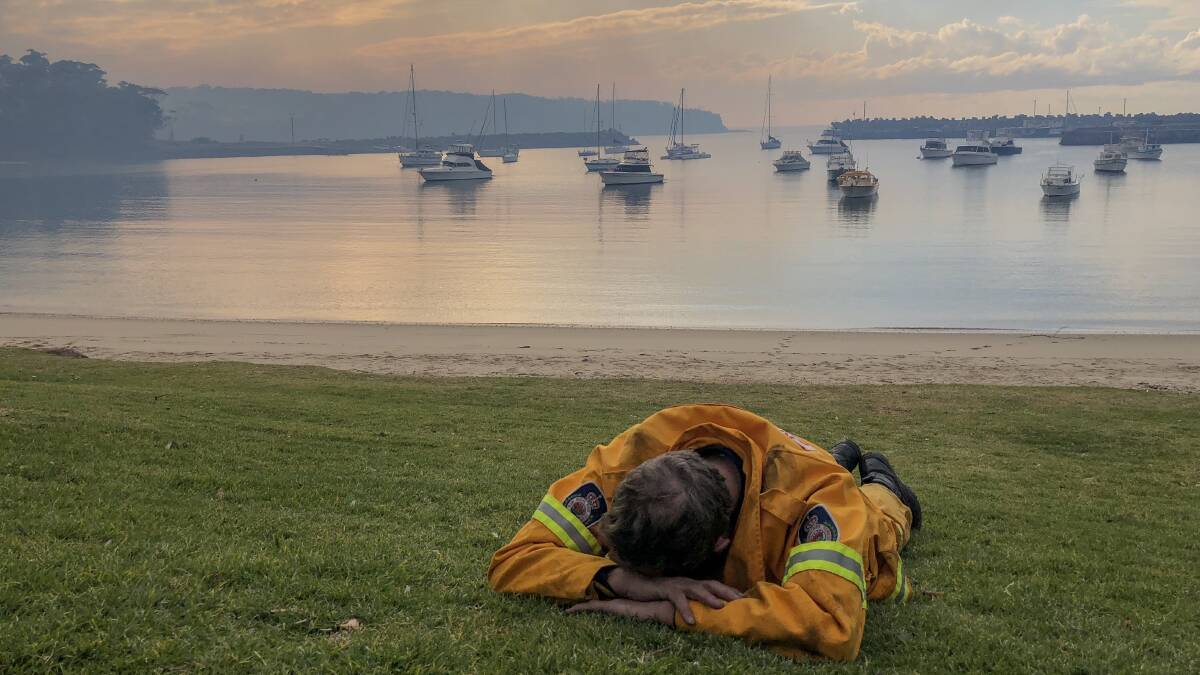 An exhausted volunteer firefighter grabs some shut-eye at Ulladulla Harbour during the height of the 2018 bushfire emergency.
